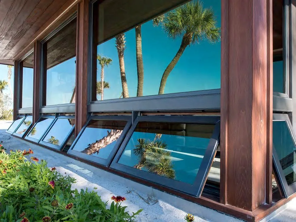 Coastal house with palm trees and aluminum awning windows